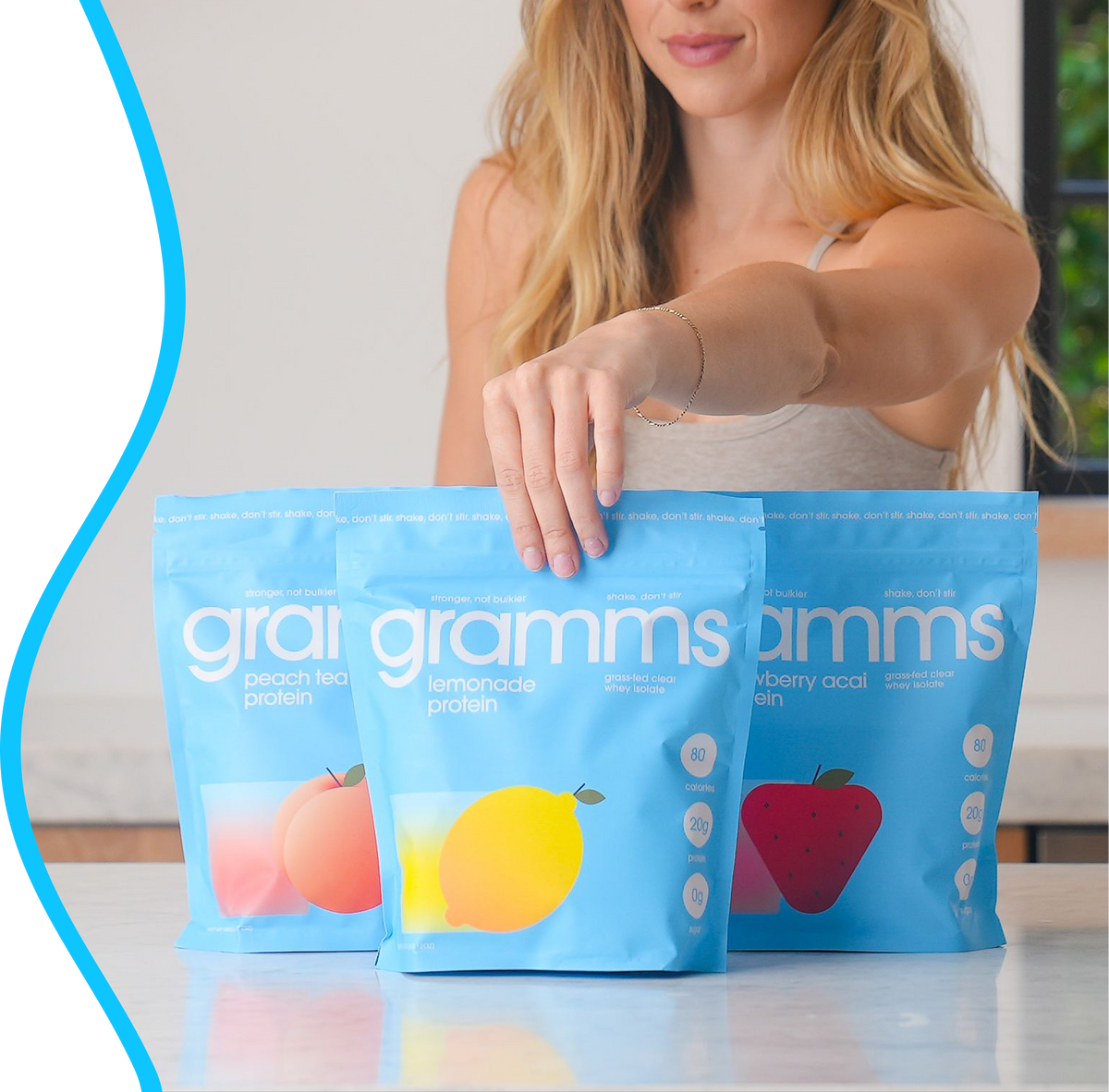 Three bags of gramms clear whey protein and a gramms shaker on a kitchen counter